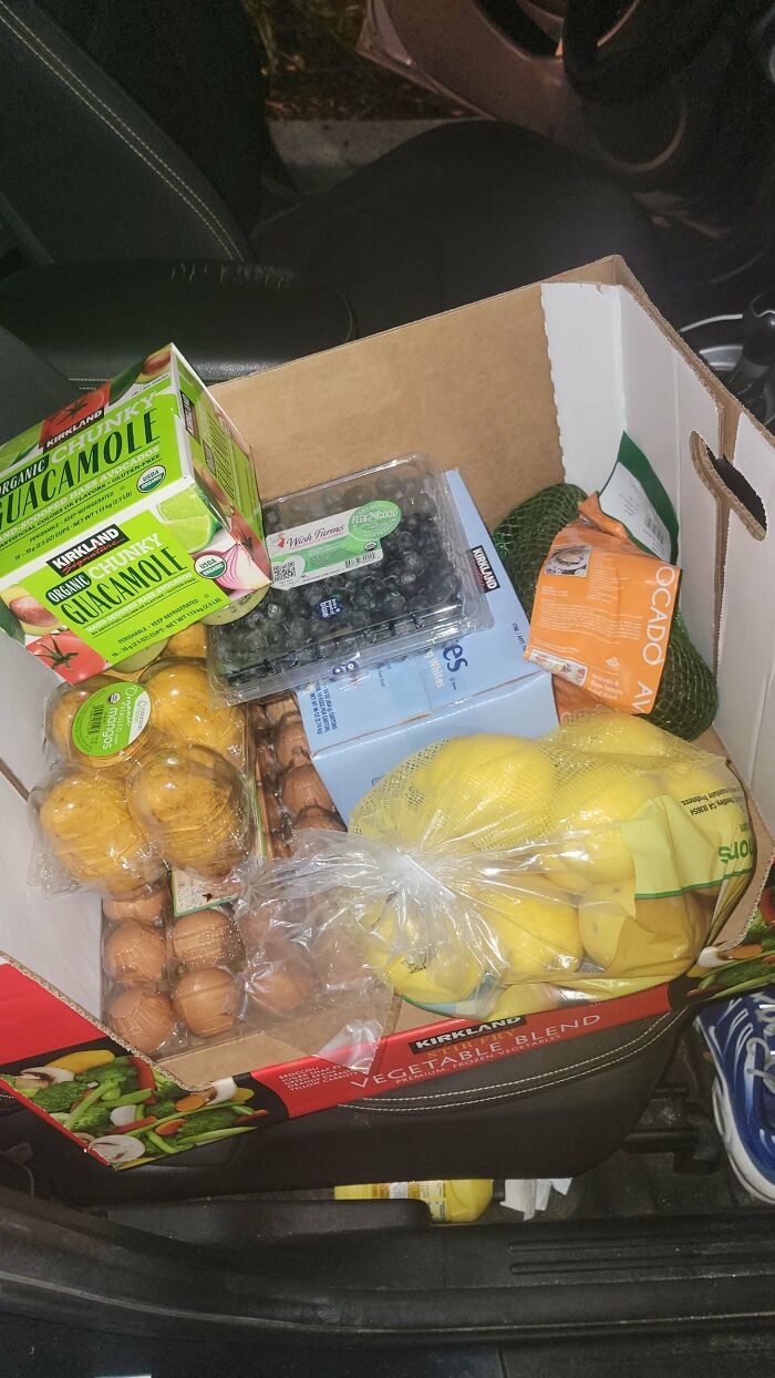 Instacart shopper's grocery haul with eggs, guacamole, blueberries, and lemons in a car seat.