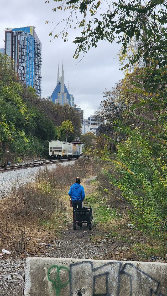 Instacart shopper walking along a train track path with skyscrapers in the background.
