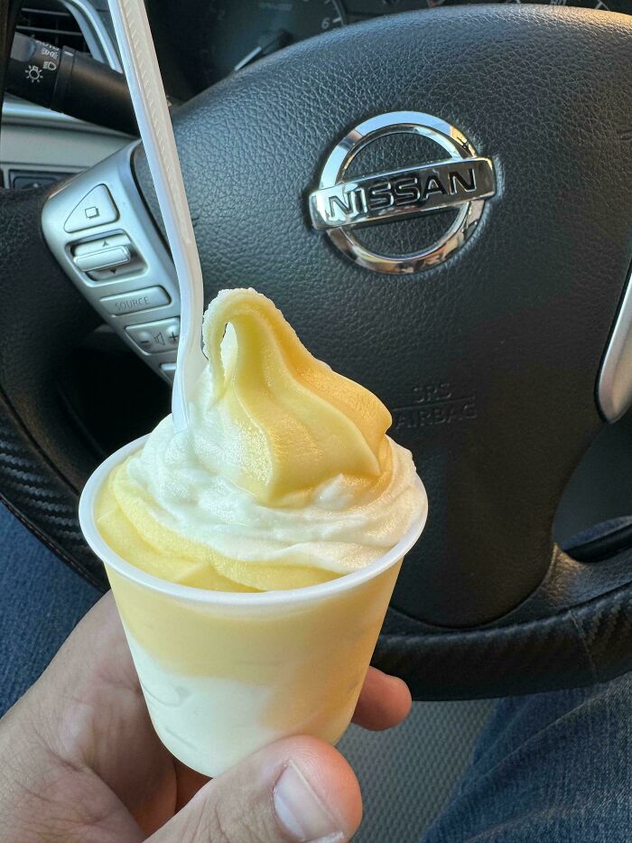 Instacart shopper holding a swirled ice cream cup with a steering wheel in the background.