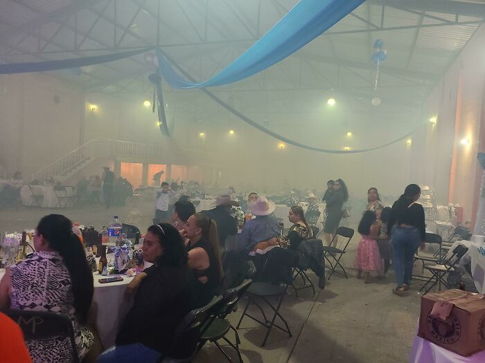 Guests sitting at tables in a smoky wedding venue, creating an uncomfortable atmosphere, fitting the theme of terrible guests.