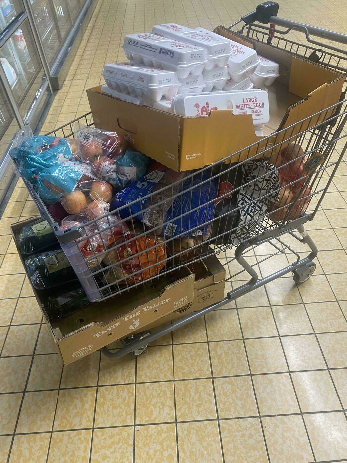 Shopping cart filled with boxes of eggs and groceries at a supermarket, a scene familiar to Instacart shoppers.