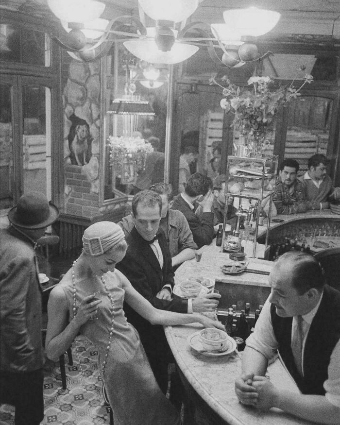Historic bar scene with elegantly dressed patrons and bartender, creating a lively atmosphere from the past.