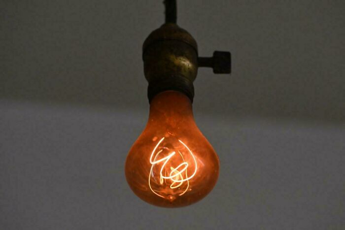 Old incandescent light bulb glowing warmly, showcasing vintage charm.
