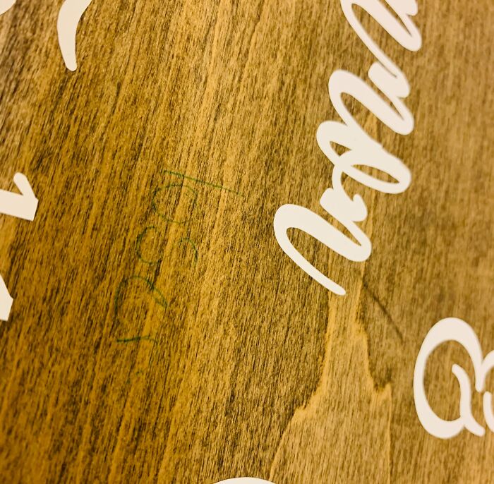 Wooden surface with "Rude" scratched in green, representing terrible wedding guests.