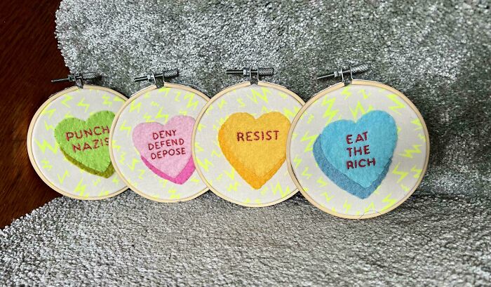 Colorful embroidered hoops with bold messages showcasing beautiful embroidery skills on soft fabric backgrounds.