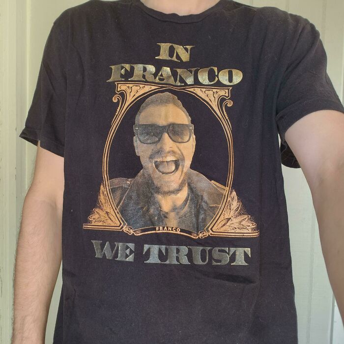 A man wearing a shirt with a graphic design featuring a smiling figure and bold text, related to future predictions.