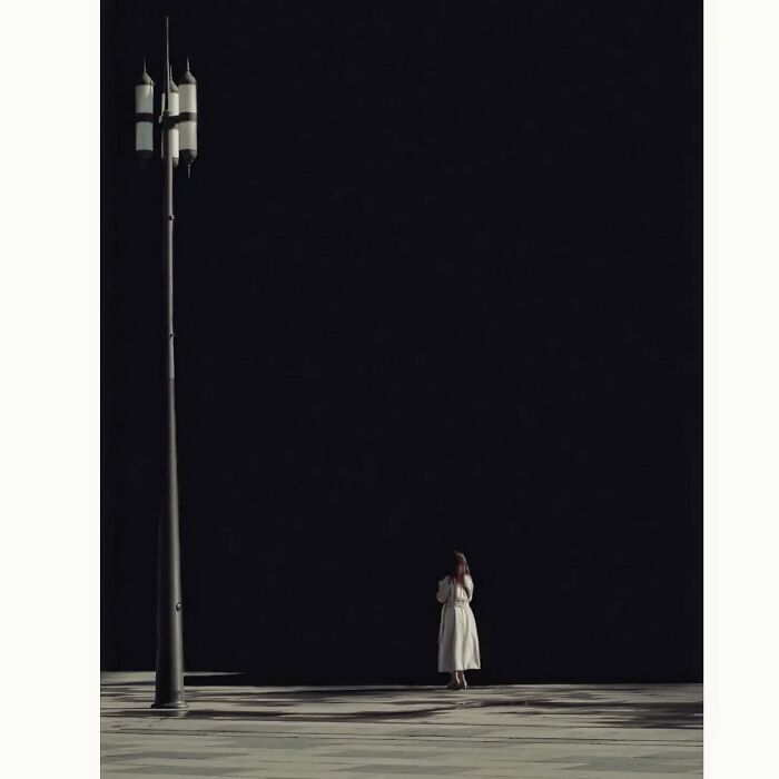 Minimalist photo capturing a quiet side of Tokyo with a solitary figure in a light coat beside a tall streetlamp.