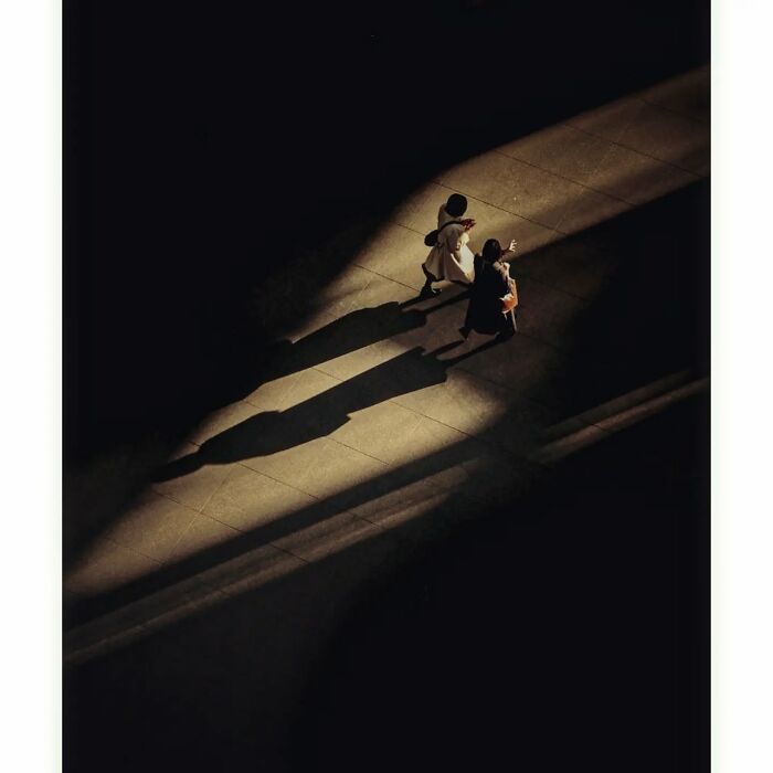 Minimalist shot of two people walking in a shadowed street, highlighting a hidden side of Tokyo.