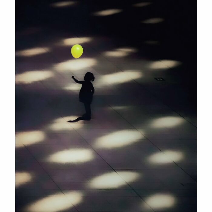A child reaching for a yellow balloon under dappled light, capturing a quiet, hidden side of Tokyo in a minimalist style.