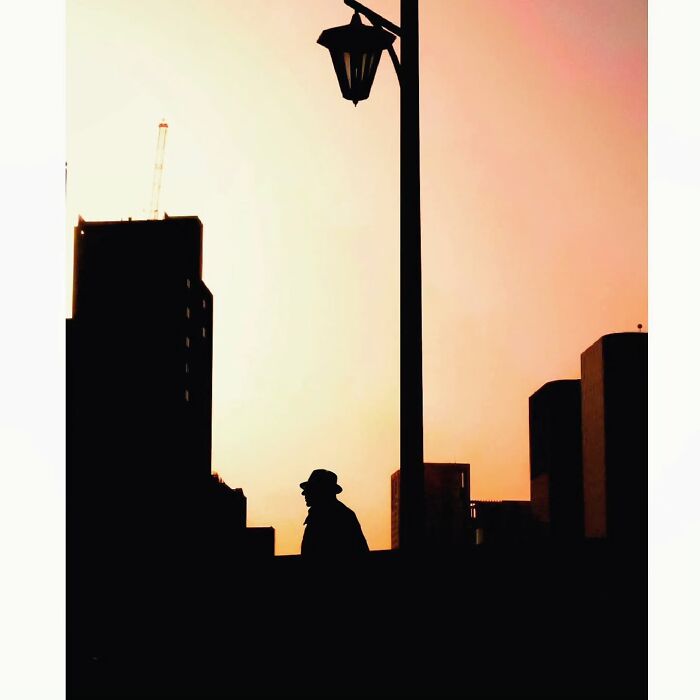 Silhouette of a person and streetlamp against a Tokyo skyline at sunset, showcasing a hidden, minimalist side of the city.