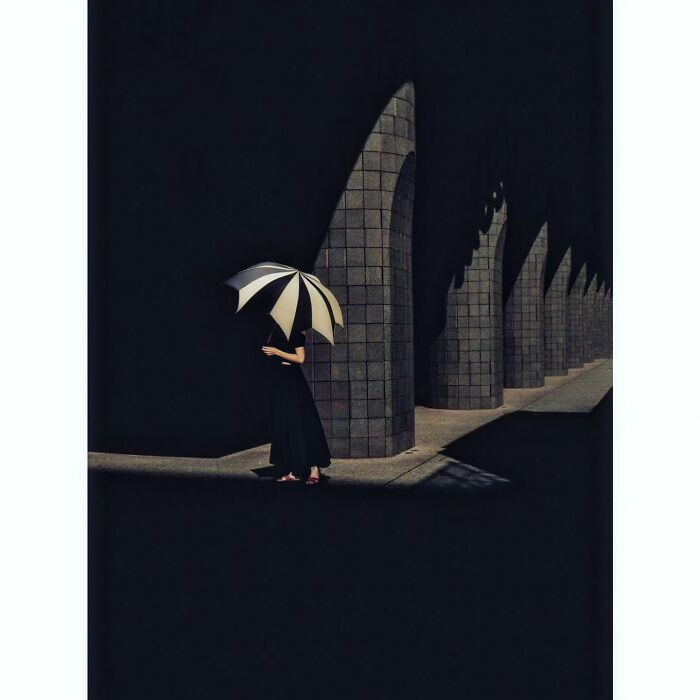 Minimalist photo of a person with an umbrella in a hidden side of Tokyo, against a backdrop of geometric shadows.