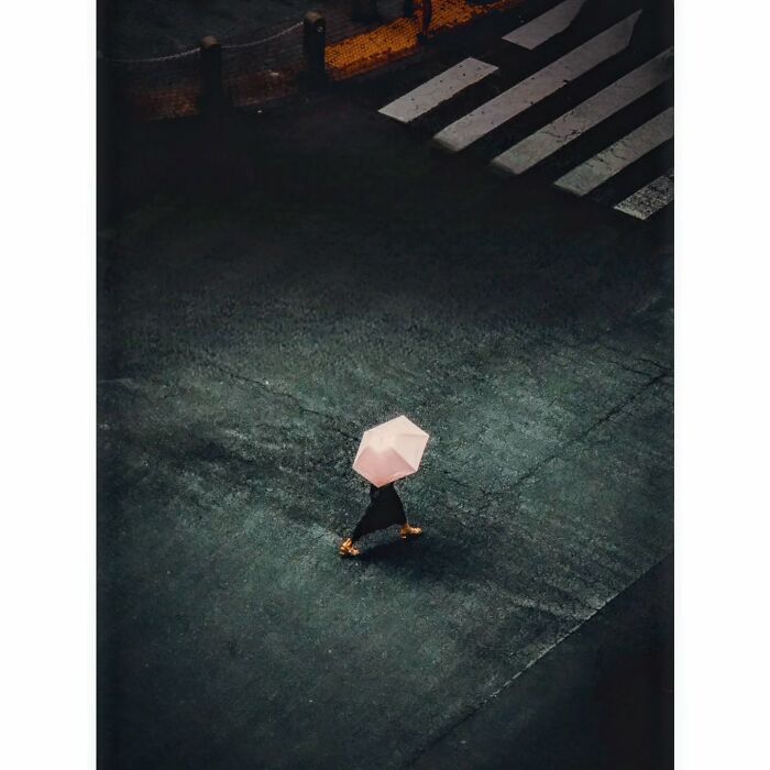 Minimalist photography of Tokyo, showing a person with a pink umbrella crossing a quiet street.