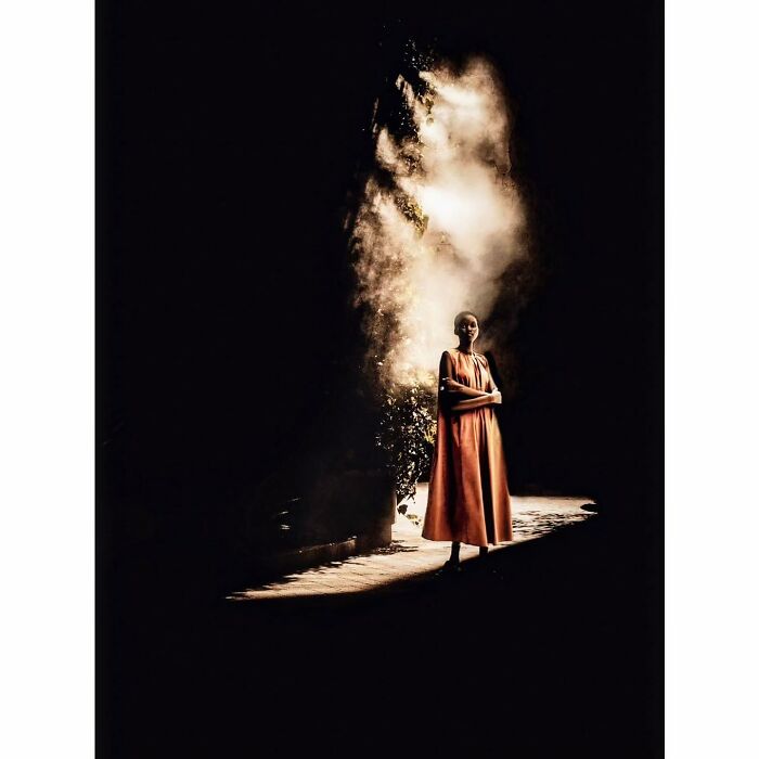 Minimalist shot capturing a quiet side of Tokyo, featuring a woman in a vibrant dress, illuminated by soft light.