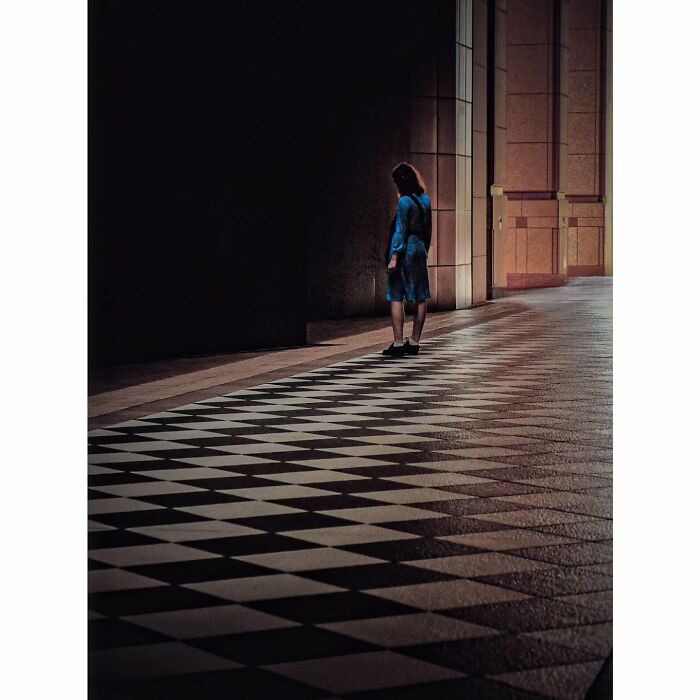 Quiet Tokyo scene with a solitary figure in blue on a geometric patterned path, capturing a hidden minimalist moment.