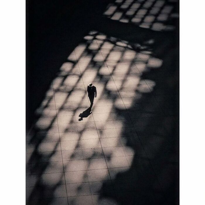 Minimalist shot of a lone figure walking through shadow patterns, capturing a quiet side of Tokyo.