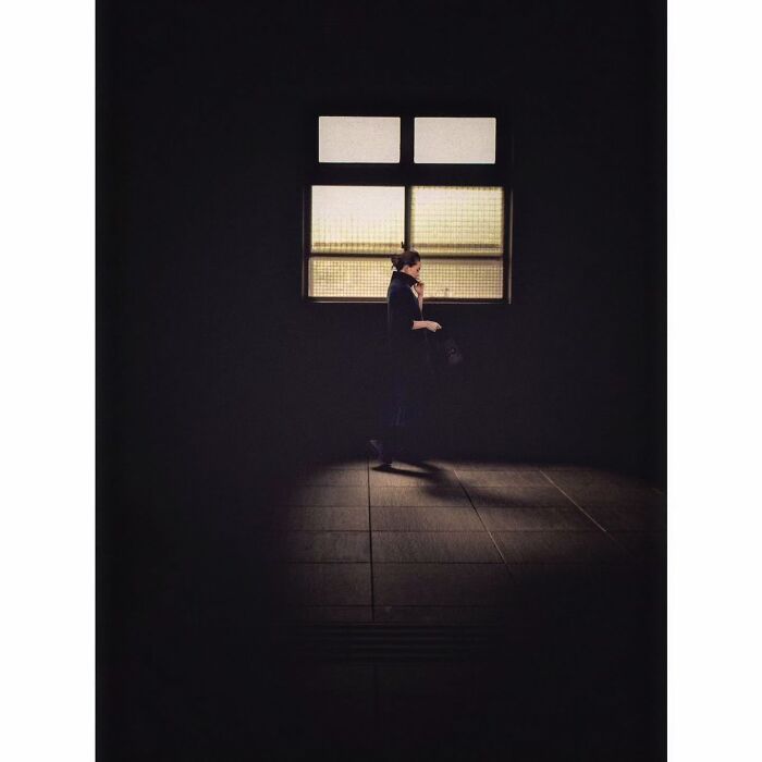 Minimalist photo of Tokyo capturing a lone figure in shadow near a softly lit window.