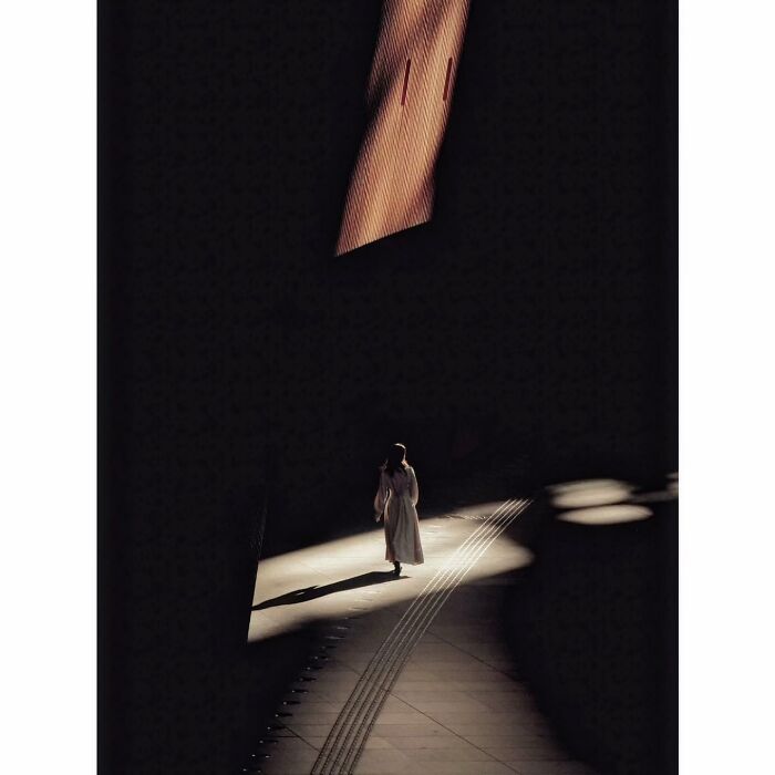 A person walks alone in a shadowy, minimalist setting, capturing a quiet side of Tokyo.