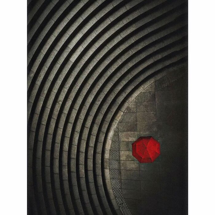 Minimalist photo of an empty concrete amphitheater in Tokyo with a lone red umbrella on the ground.