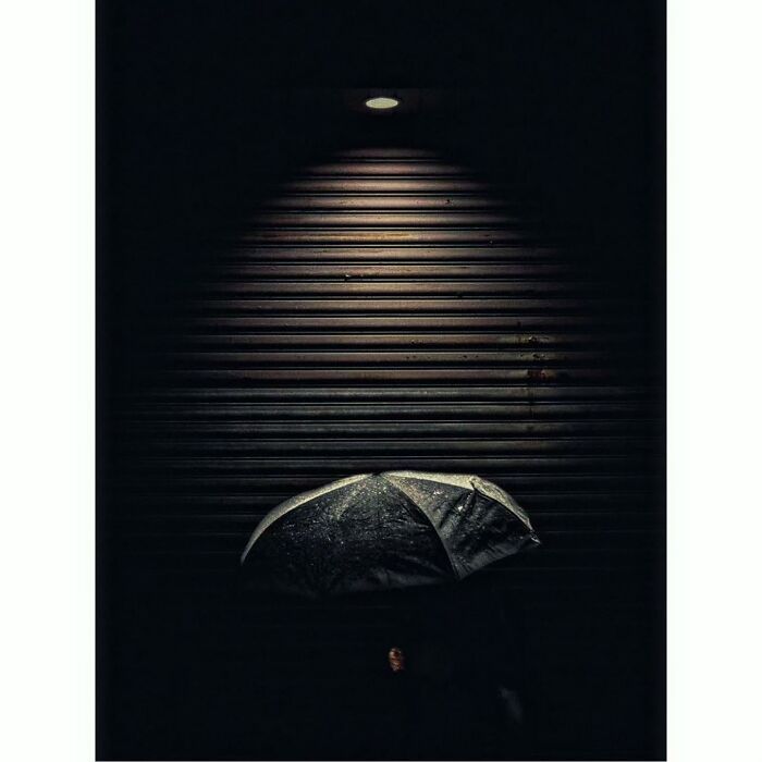 Minimalist shot of Tokyo with a person under a dimly lit umbrella, showcasing a quiet, hidden scene.