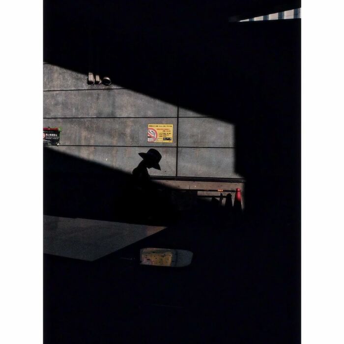 Minimalist photo capturing a shadowy figure in a quiet, hidden corner of Tokyo.