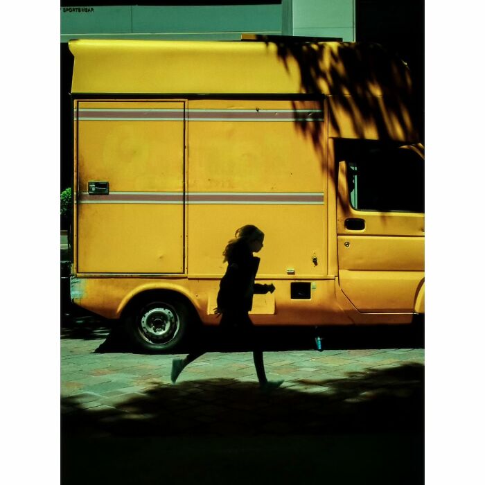 Silhouette of a person walking past a yellow van in Tokyo, showcasing minimalist photography.