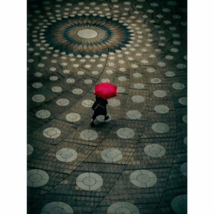 Person with red umbrella walks on patterned pavement showcasing minimalist Tokyo photography.