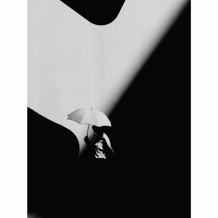 Minimalist photograph of a person with an umbrella, capturing a hidden side of Tokyo in a play of light and shadow.