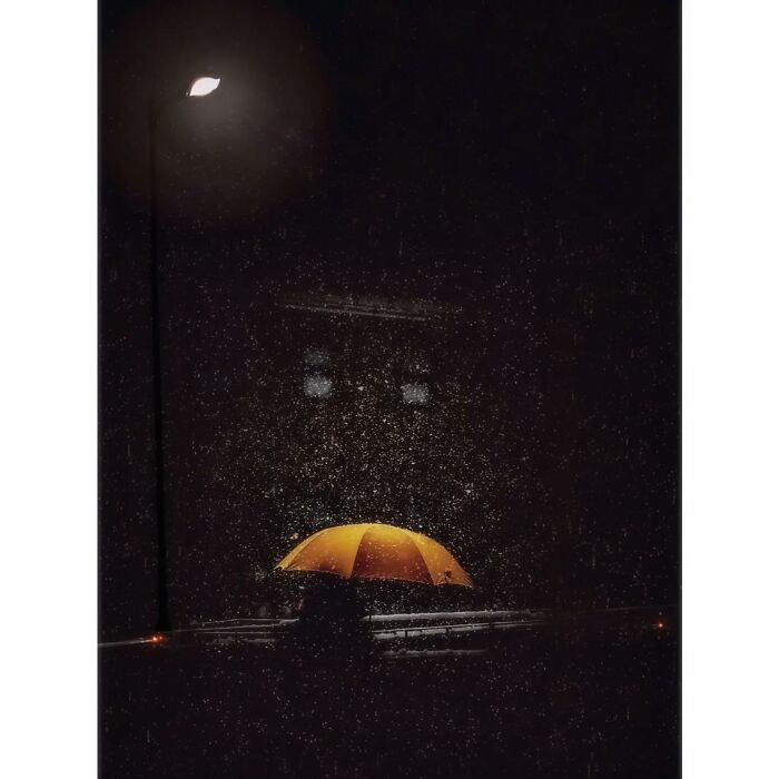 Umbrella in rain under streetlight, capturing Tokyo's quiet, hidden side with minimalist style.