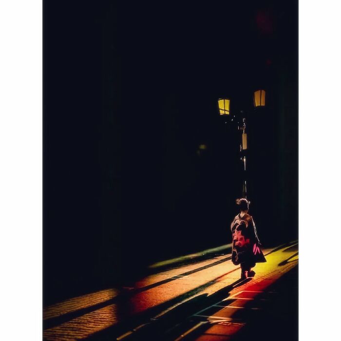 A person in traditional clothing walks under a streetlight, showcasing Tokyo's hidden minimalist beauty.