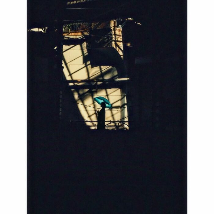 Minimalist photograph of Tokyo, showing a silhouette with a blue umbrella against geometric shadows.