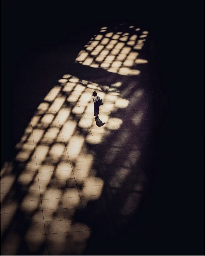 Person walking in shadowy light patterns, capturing a hidden side of Tokyo through minimalist photography.