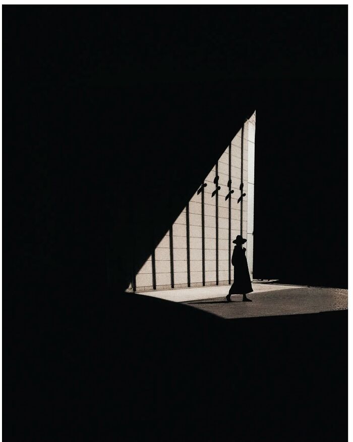 Minimalist shot of a person walking in a shadowy Tokyo passage, highlighting a hidden side of the city.