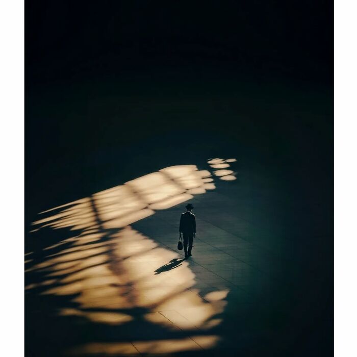 Minimalist view of Tokyo with a lone person walking through a sunlit space, casting shadows on the ground.