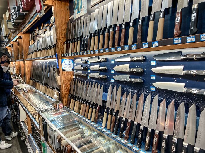 Japanese knives displayed on shelves in a store, showcasing craftsmanship and variety.