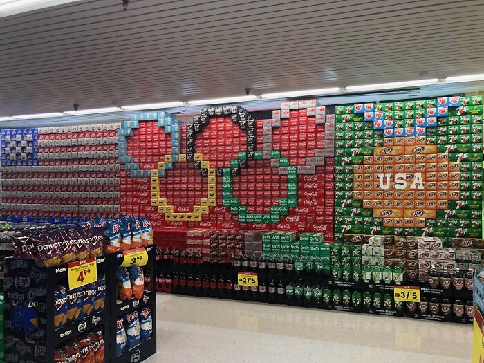 Soda boxes arranged as Olympic rings and USA flag display in a mildly interesting supermarket aisle.