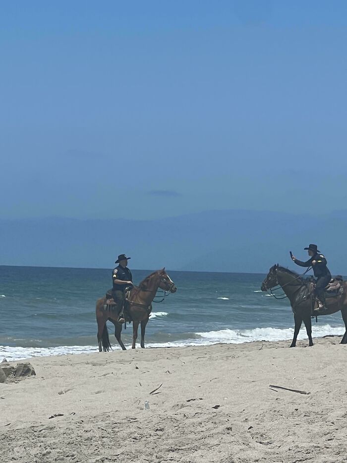 Two horseback riders on a beach, creating a mildly interesting contrast against the ocean backdrop.