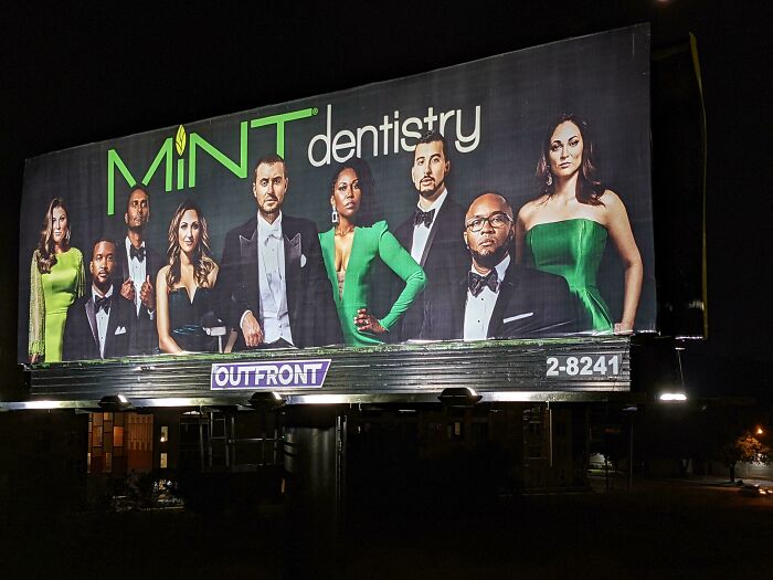 Billboard of Mint Dentistry featuring people dressed in elegant green and black attire at night, mildly interesting scene.