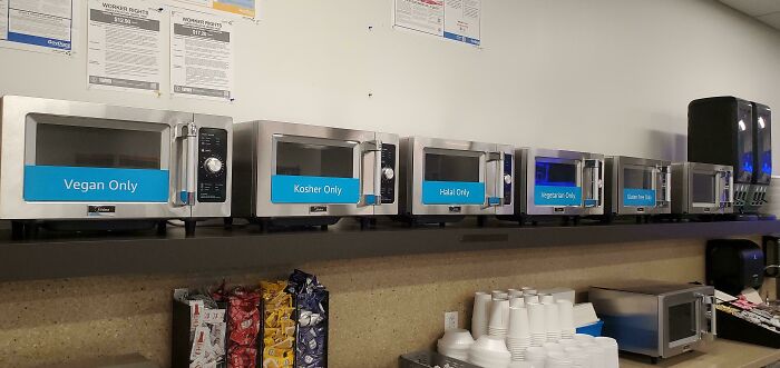 Multiple microwaves labeled for specific dietary preferences in an office kitchen; a mildly interesting sight.