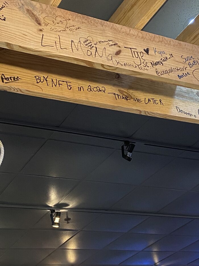 Graffiti on a wooden beam reading "BUY NFTs in 2022," illustrating predictions aged bad.