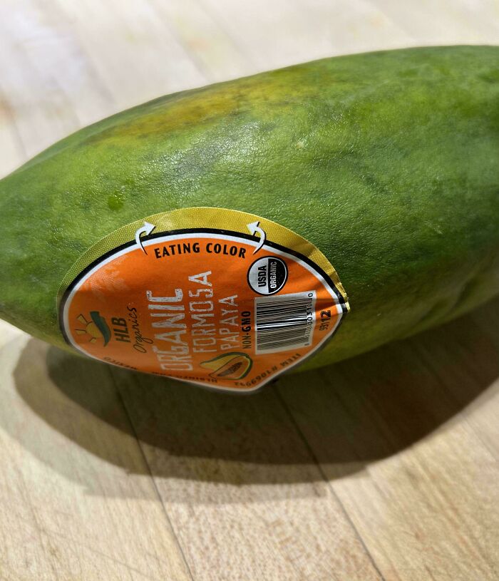 Organic Formosa papaya with eating color label on a wooden surface.