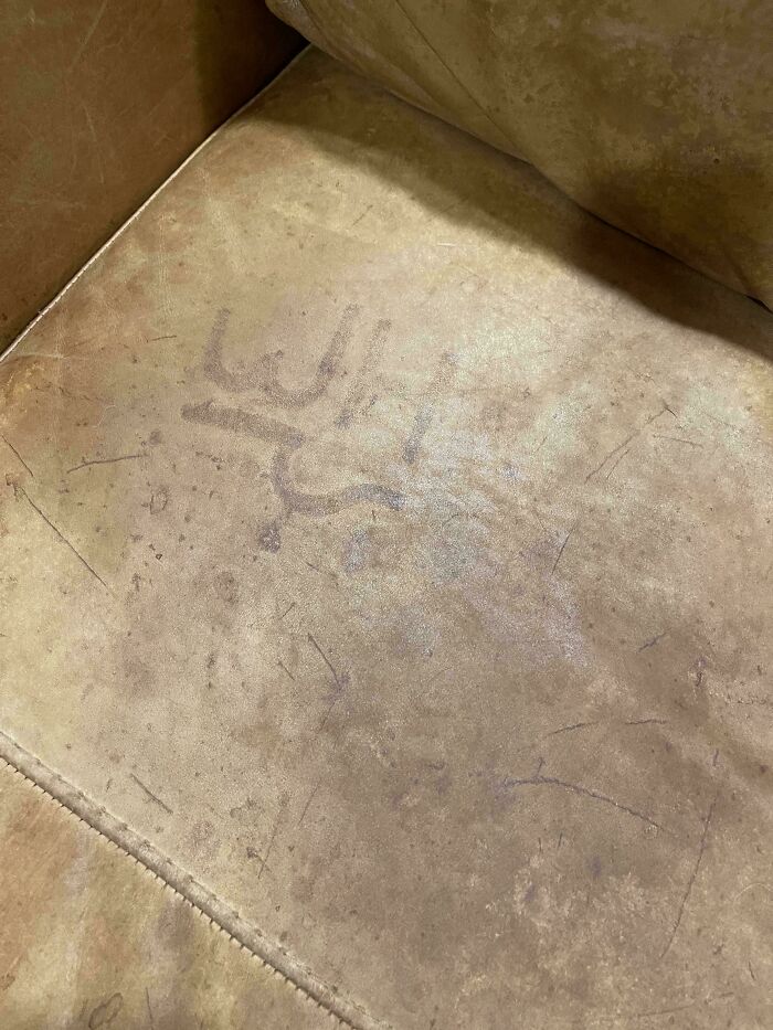 "Mildly interesting faded imprint on an old beige couch, showing faint markings and wear over time."