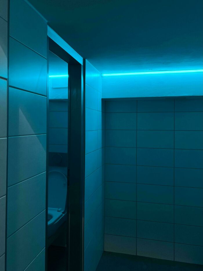 Dimly lit bathroom with blue LED lighting on tiled walls, showcasing a mildly interesting ambiance.