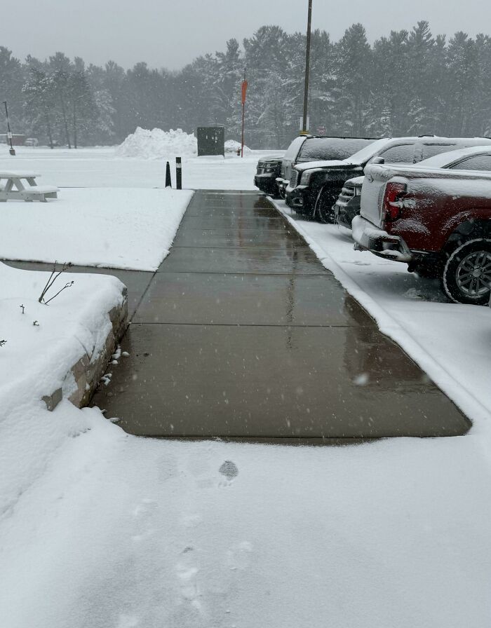 Snowy scene with a clear path surrounded by parked cars, highlighting mildly interesting contrast.