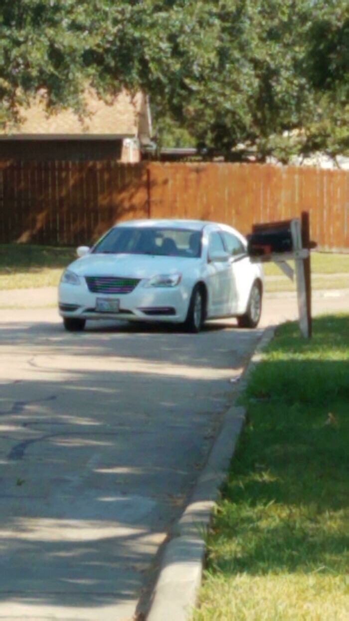 A white car parked inconsiderately in front of a mailbox, highlighting terrible neighbors.