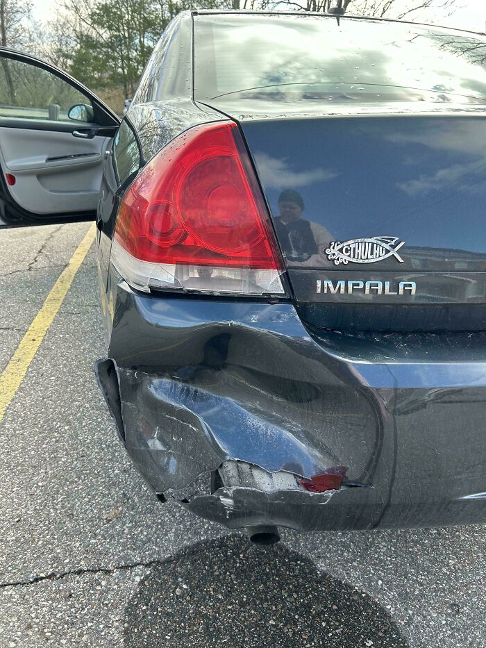 Damaged Impala bumper in parking lot, possibly due to terrible neighbors.