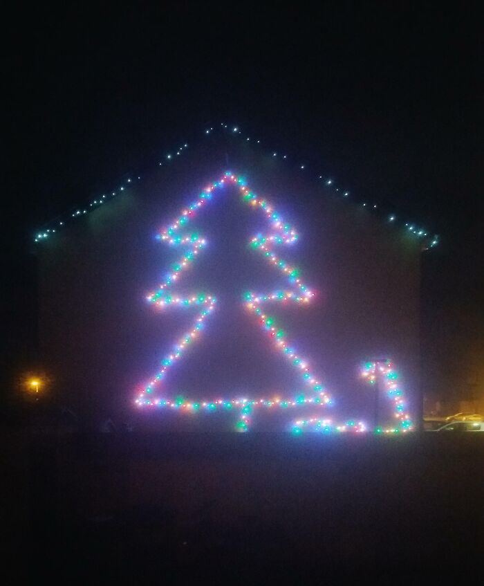 House decorated with colorful Christmas lights forming a tree, showcasing infuriating terrible neighbors' holiday display.