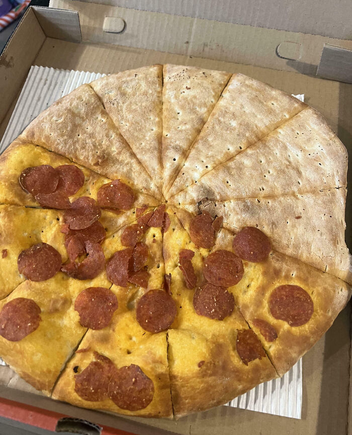 Pizza in a box with pepperoni sparsely covering the surface, illustrating food scams with uneven topping distribution.