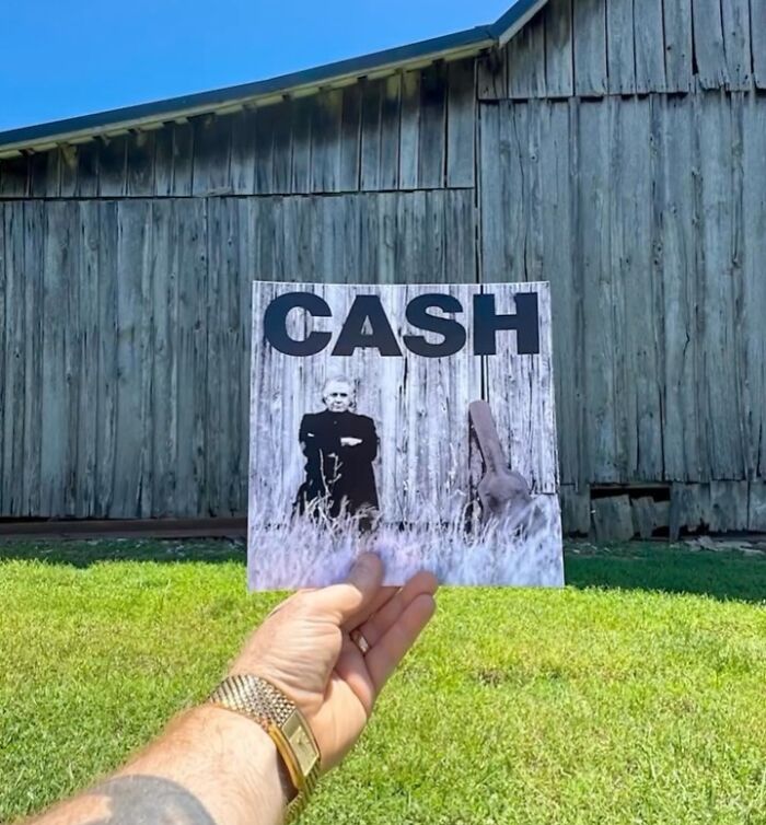 Hand holding a Cash album cover in front of an old barn, highlighting iconic location and legend connection.