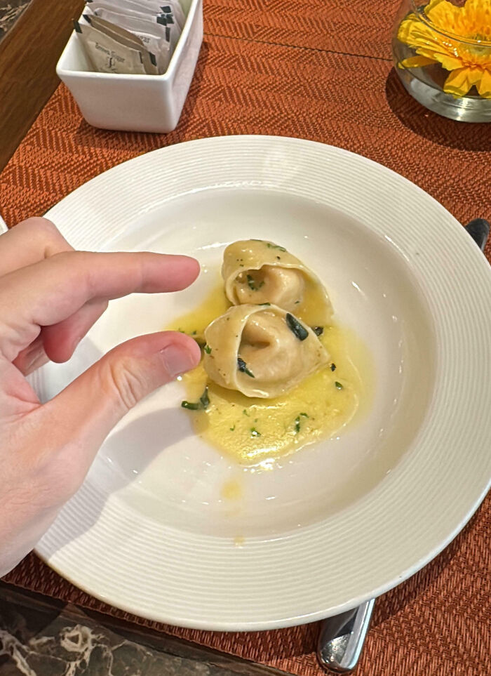 Tiny portion of ravioli on a plate, illustrating food scams in dining experiences.