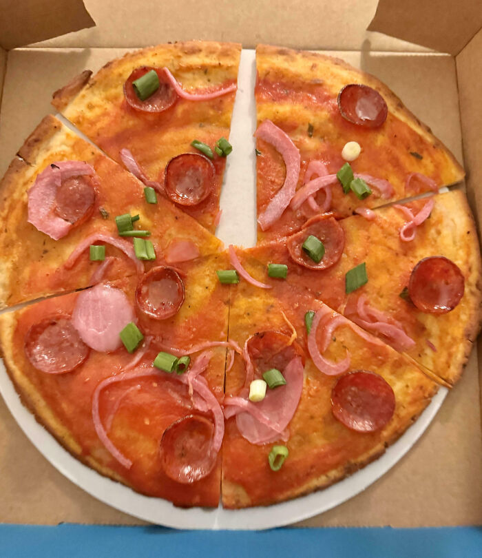 Pizza with sparse toppings, showcasing a food scam with minimal pepperoni and vegetables.